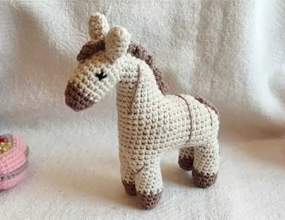 Cute horse amigurumi free crochet pattern showing a small handmade crochet horse toy in neutral colors, perfect for nursery decor or baby gift