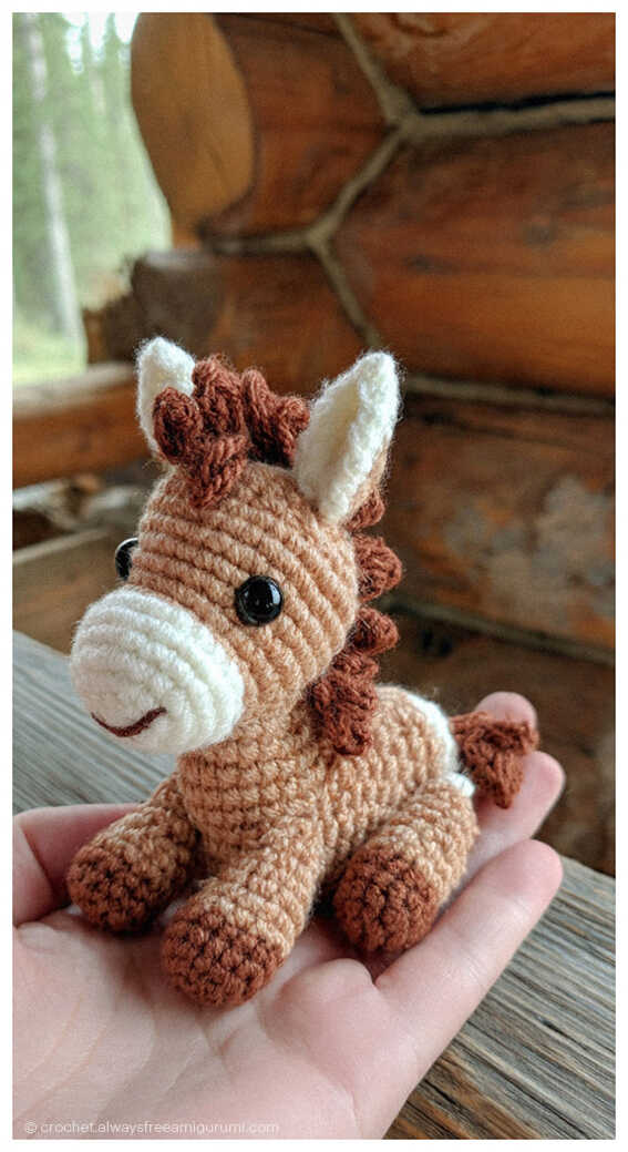 Brown crochet horse amigurumi sitting in a hand, handmade nursery decor and baby gift inspiration